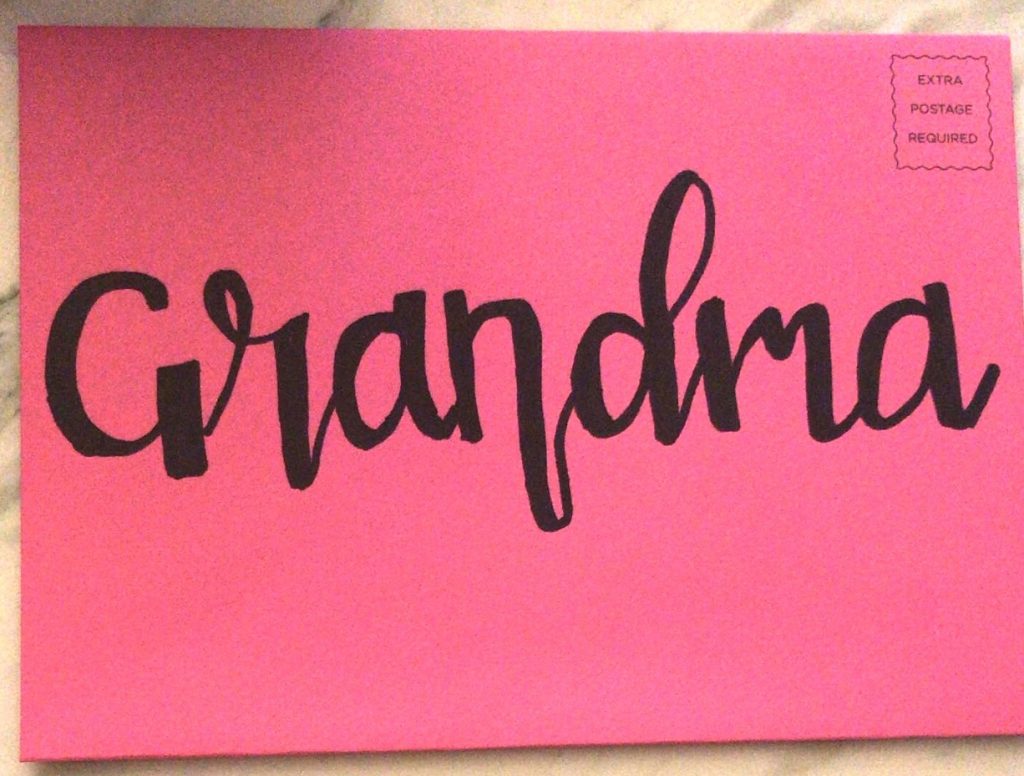 Hand lettering with a Sharpie Marker writing Grandma on a card envelope